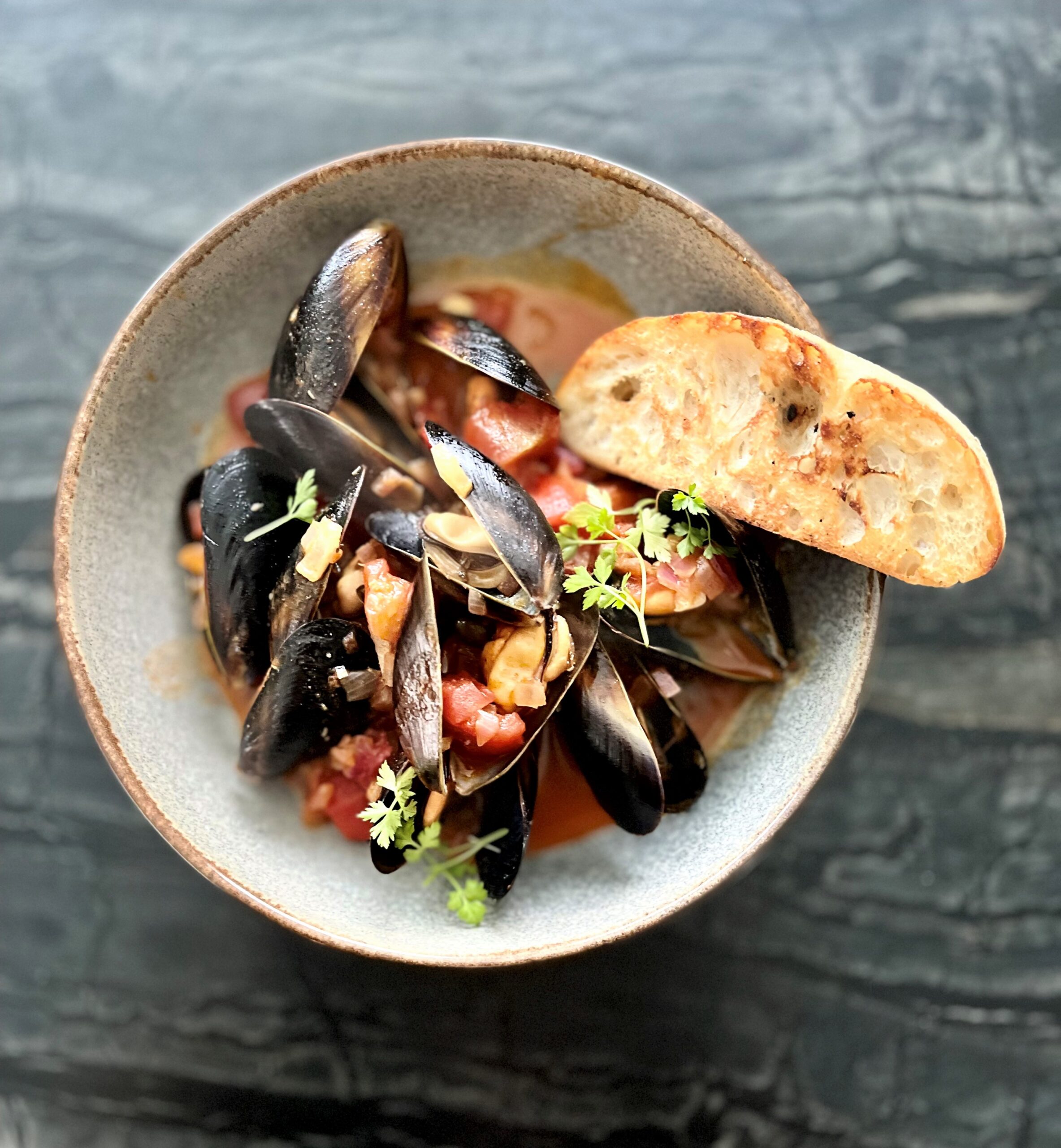 Mussels steamed in tomatoes, capers, & white wine broth