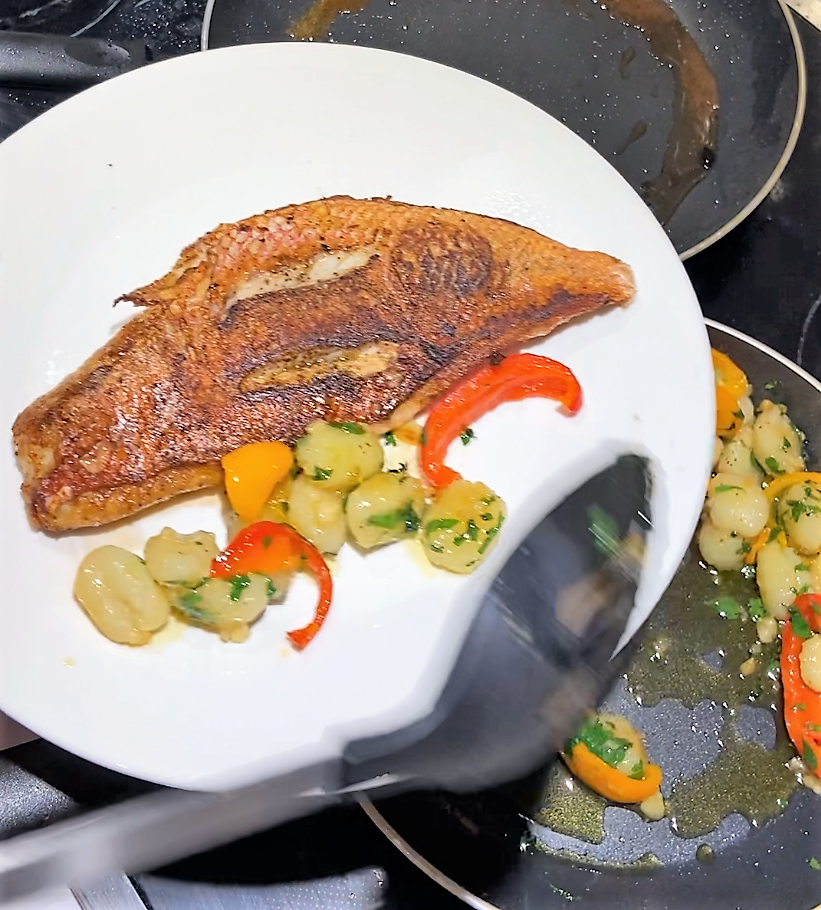 plate red snapper fillet together with the gnocchi and belle peppers