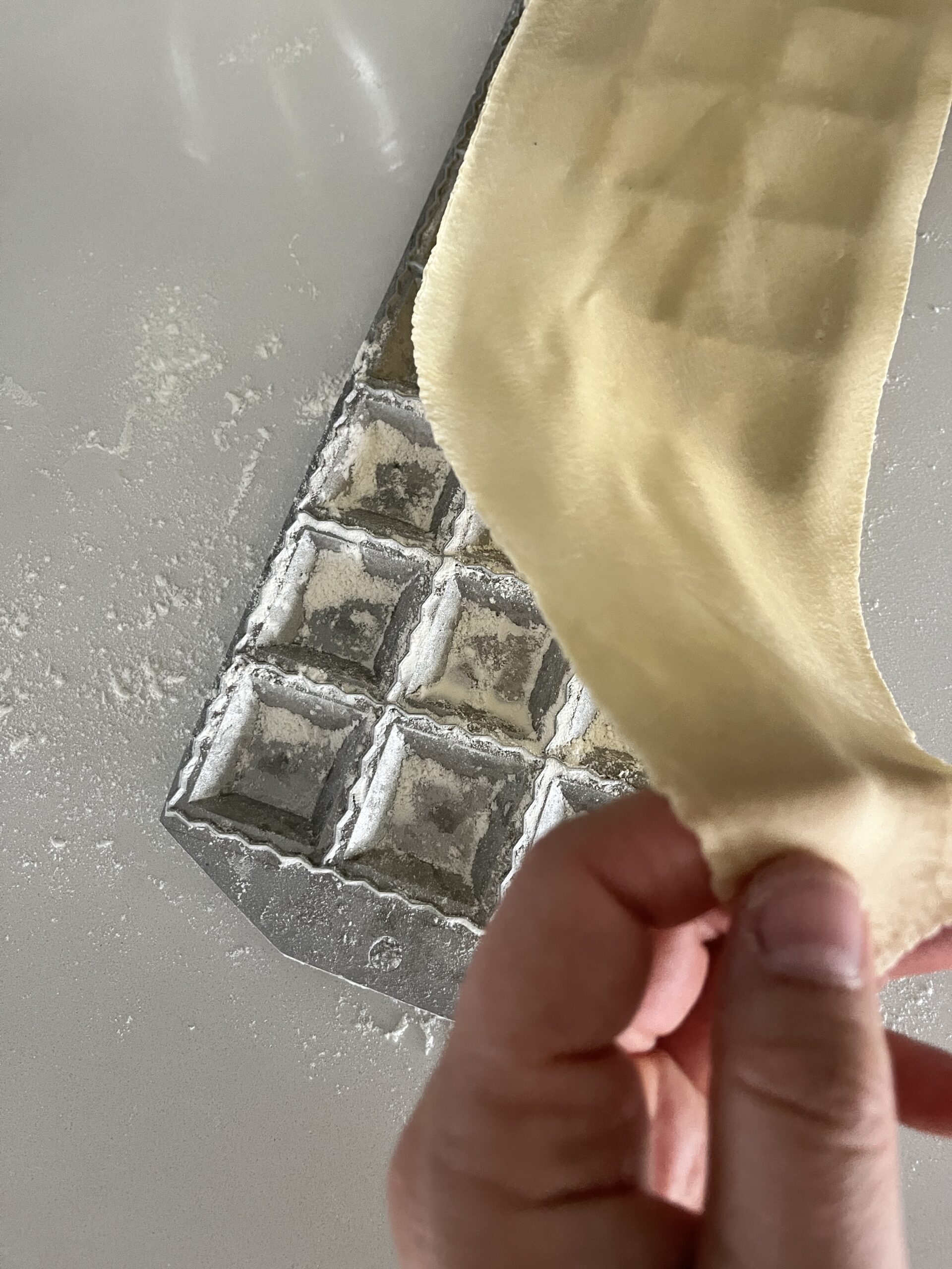 lay rolled out pasta sheet over the ravioli maker