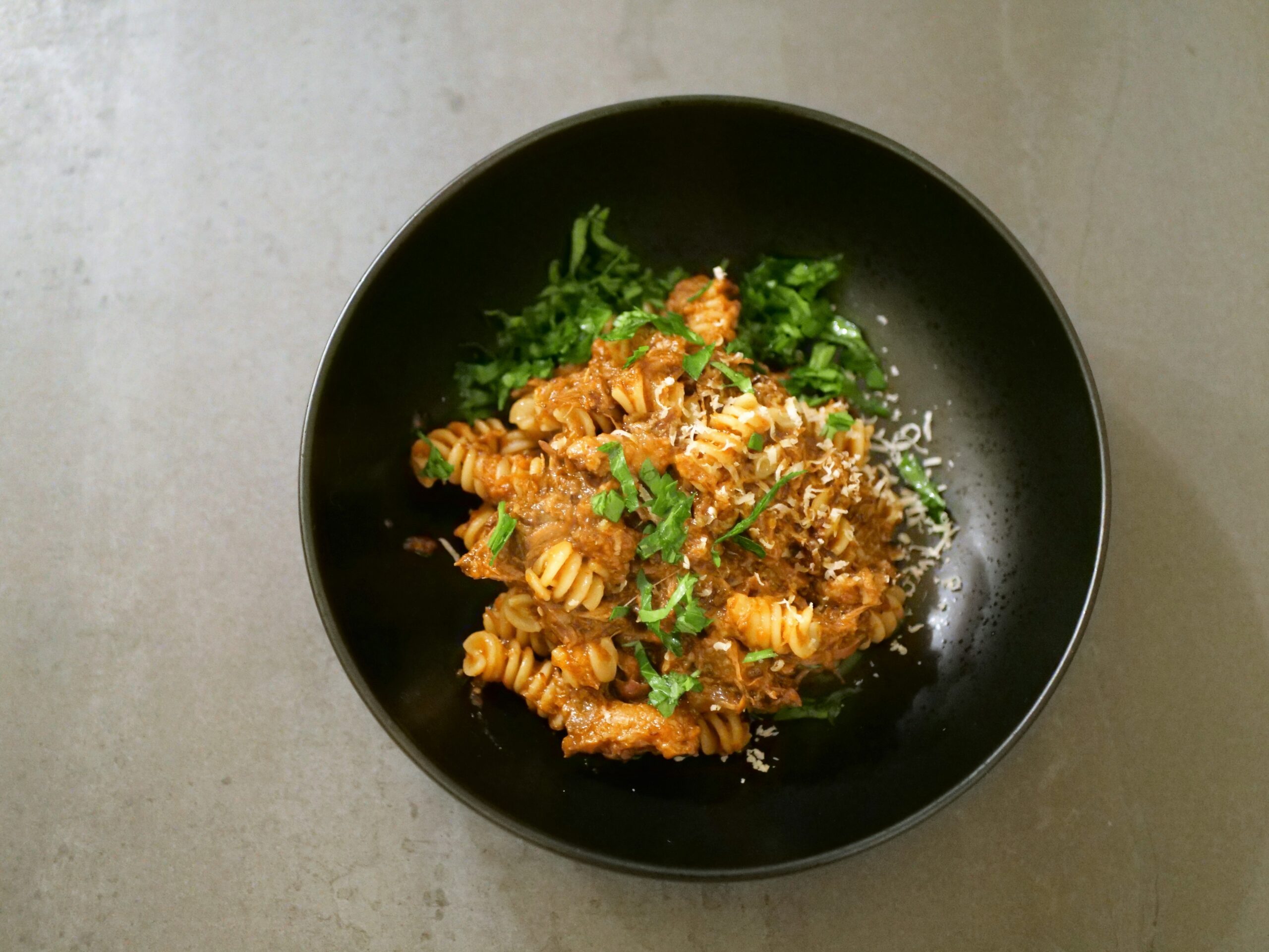 sprinkle parsley and cheese over pasta with braised oxtail ragu sauce 