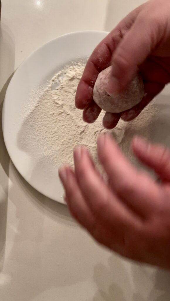 using your hands lightly dust rolled meatballs with flour