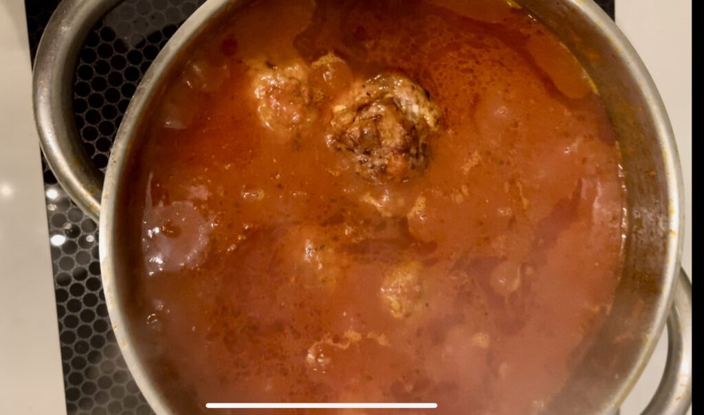 cook meatballs submerged in tomato sauce